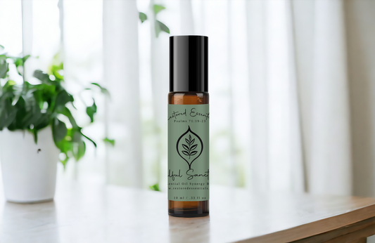 Soulful Sanctuary Essential Oil Roller Blend Bottle on a table with green plants and white curtain in the background.