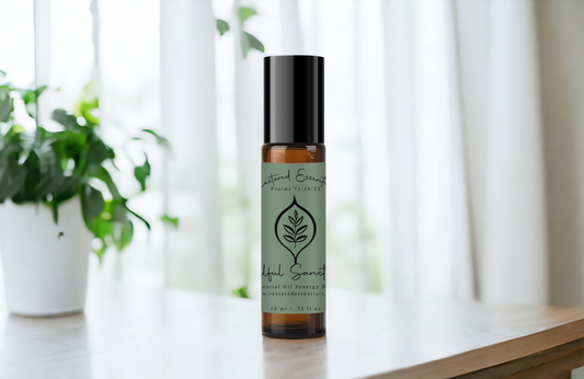 Soulful Sanctuary Essential Oil Roller Blend Bottle on a table with green plants and white curtain in the background. 