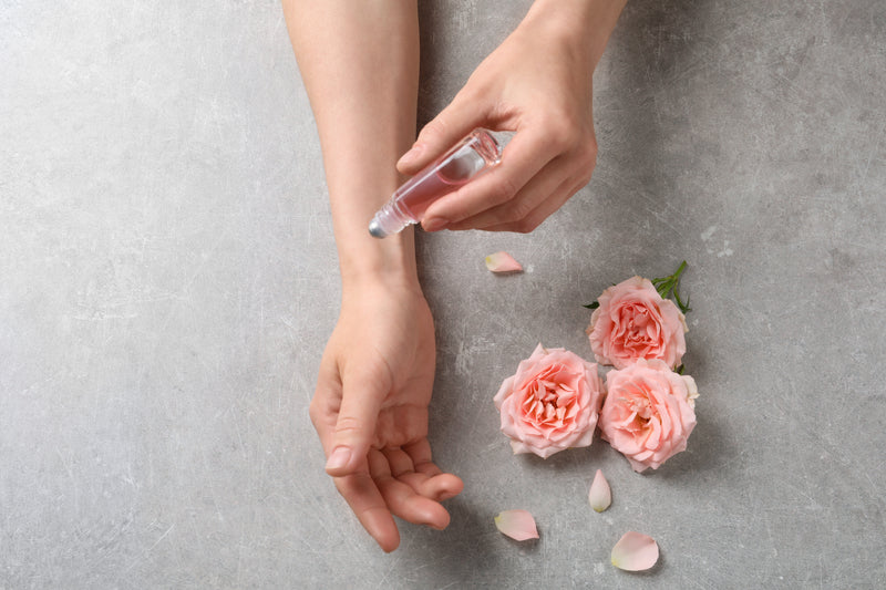 Lady using roller on wrists with pink flowers