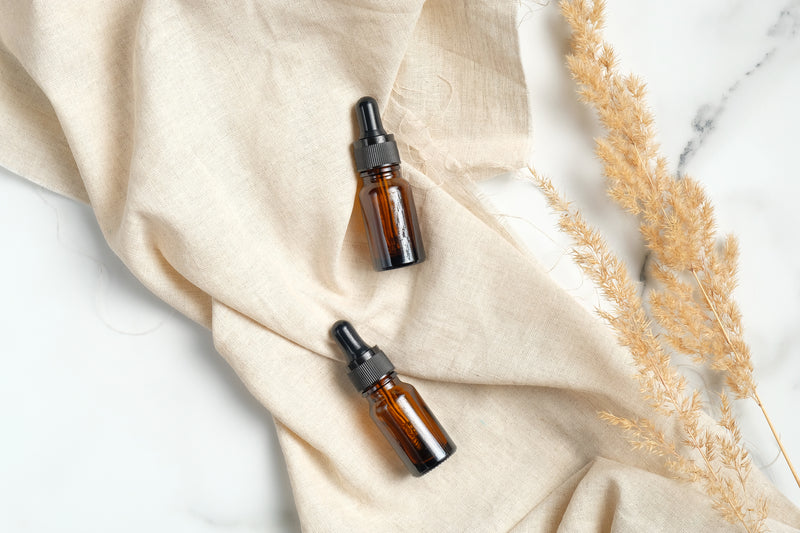 Oil dropper bottles in tan linen on marble table